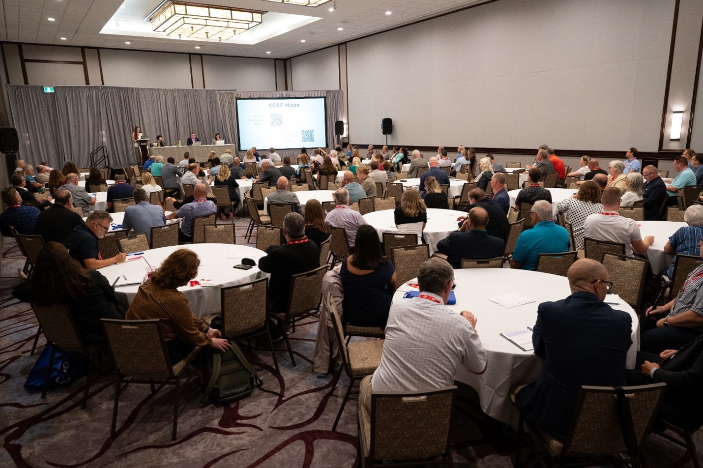 A crowd watching a presentation on stage at the AMO 2025 conference