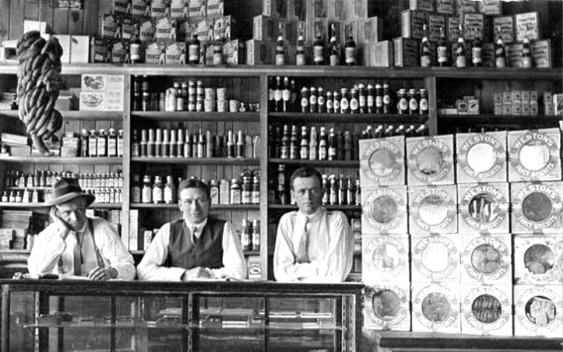 Black and white photo of men standing at a store counter