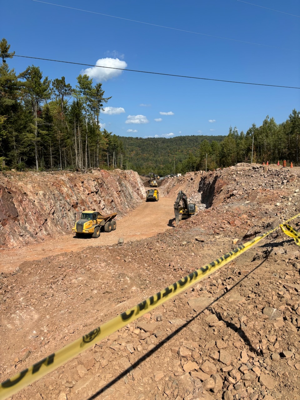 Long ditch with dump trucks in it