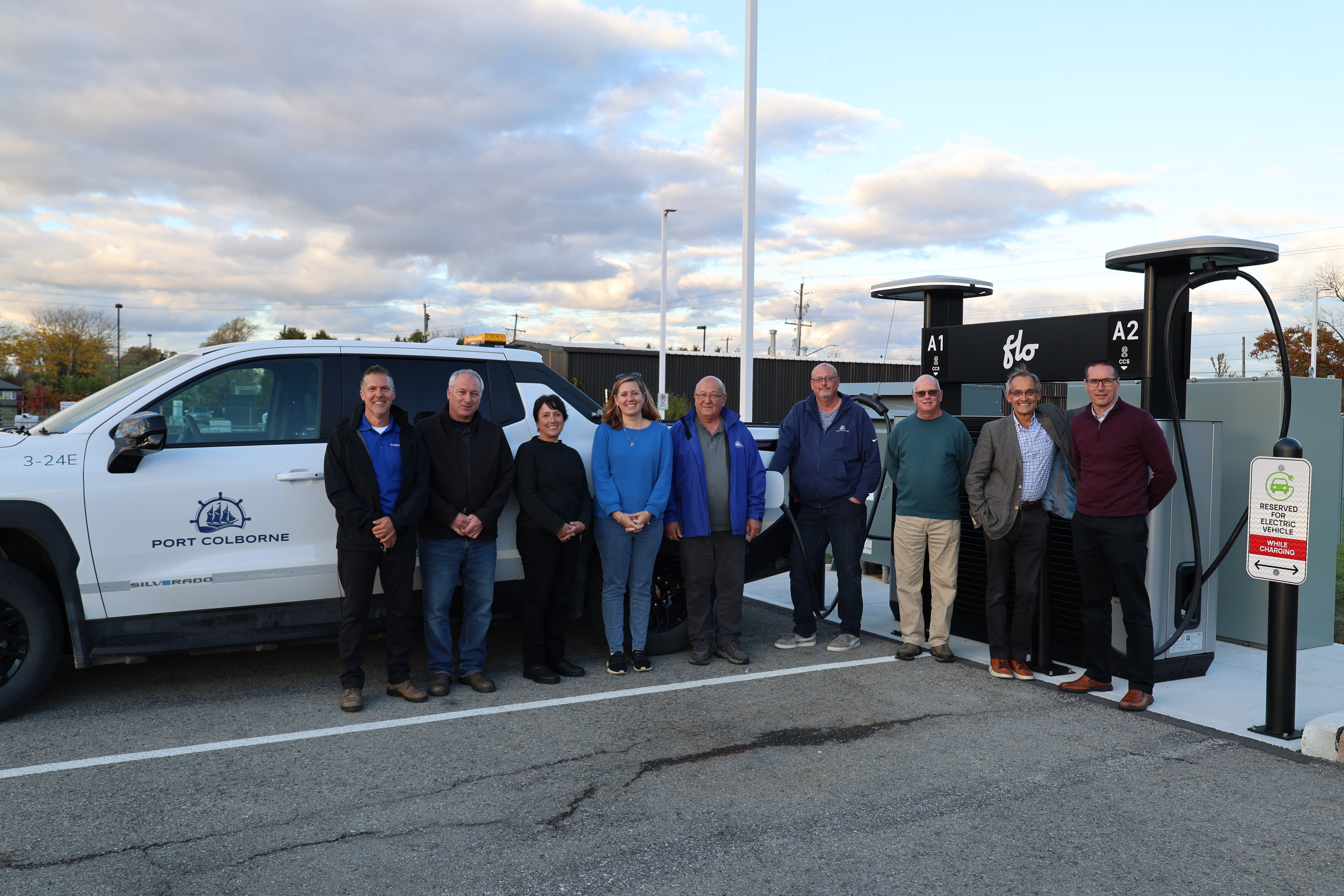 A group of municipal staff standing in front of an electric vehicle charging station