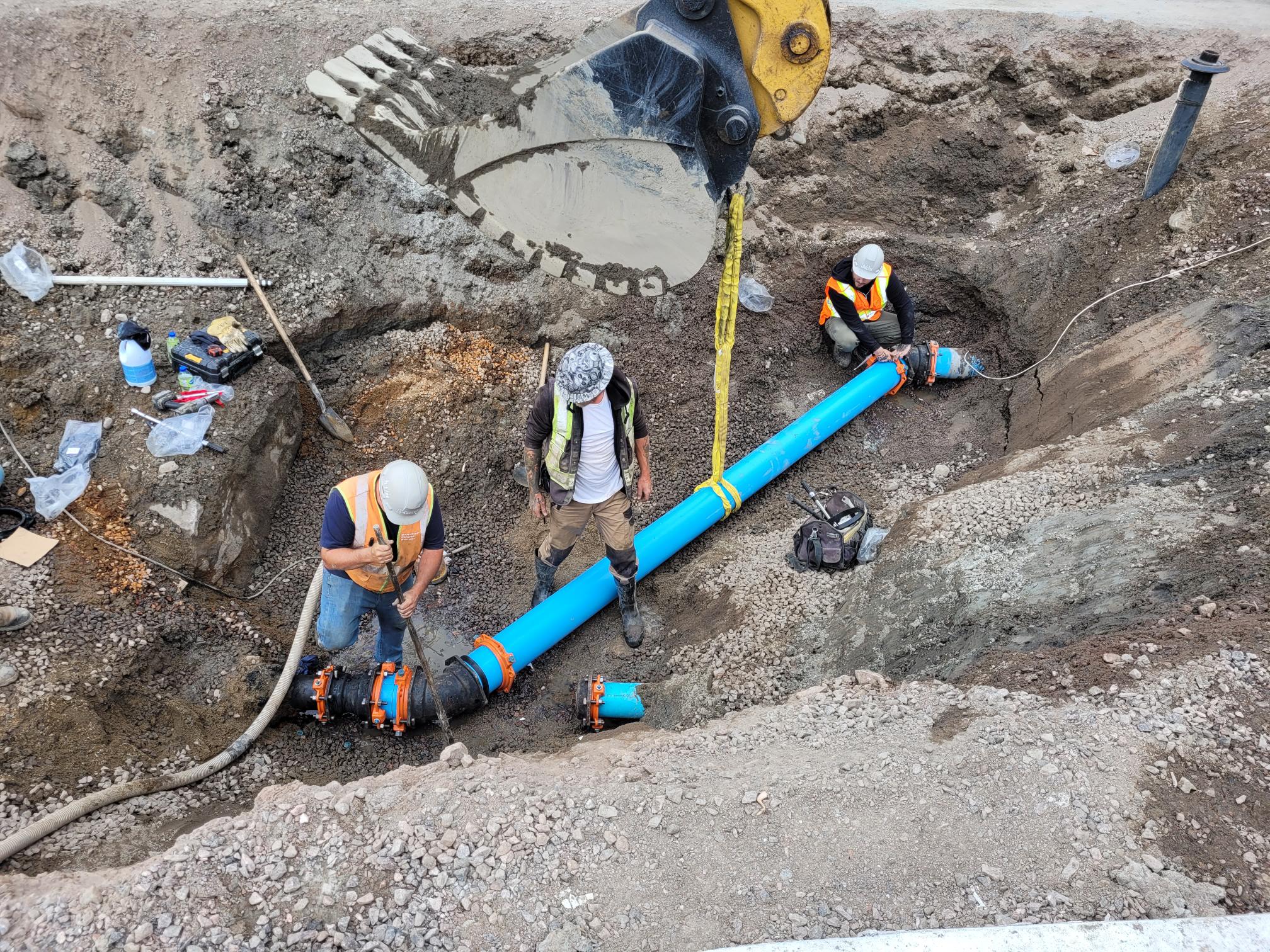 Construction workers in a ditch working on a pipe