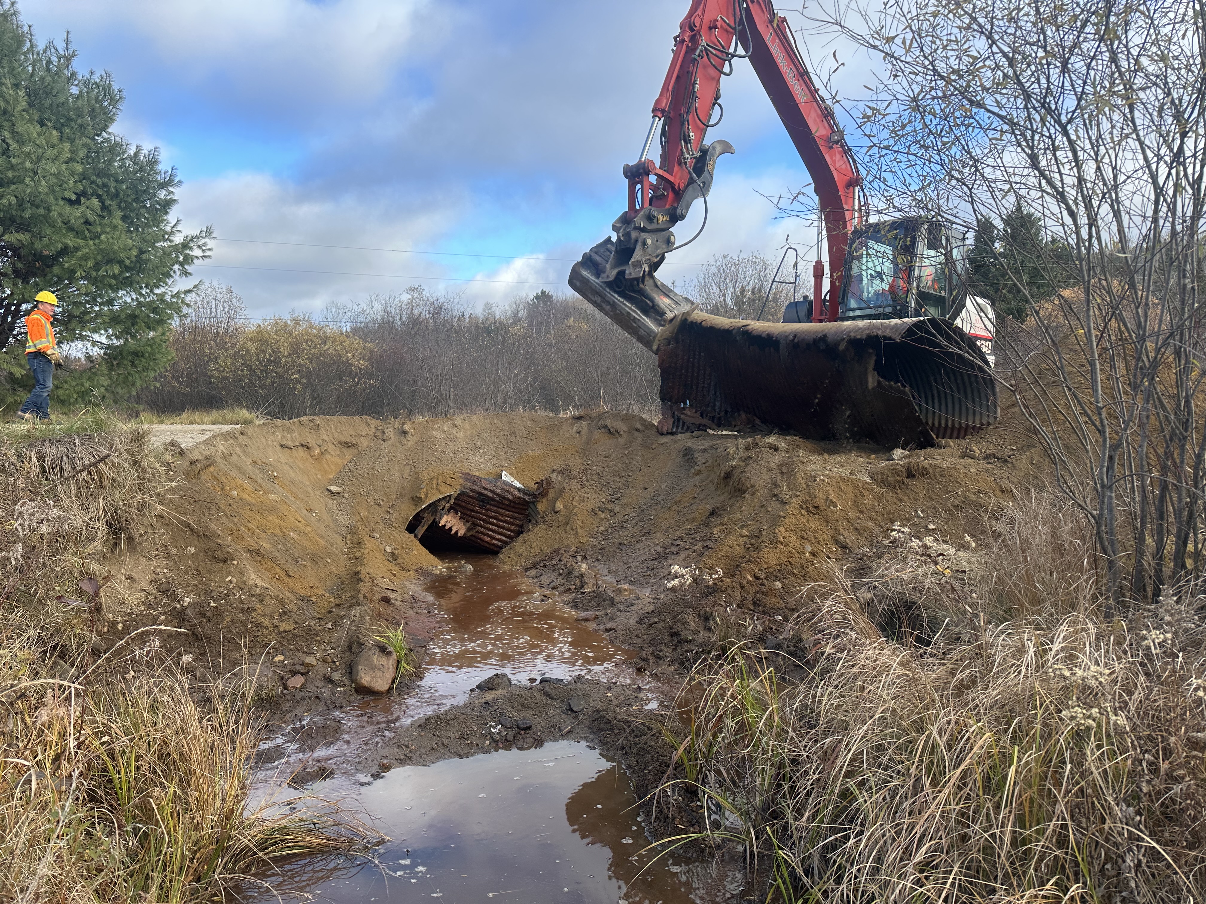 A digger moving a drainage pipe