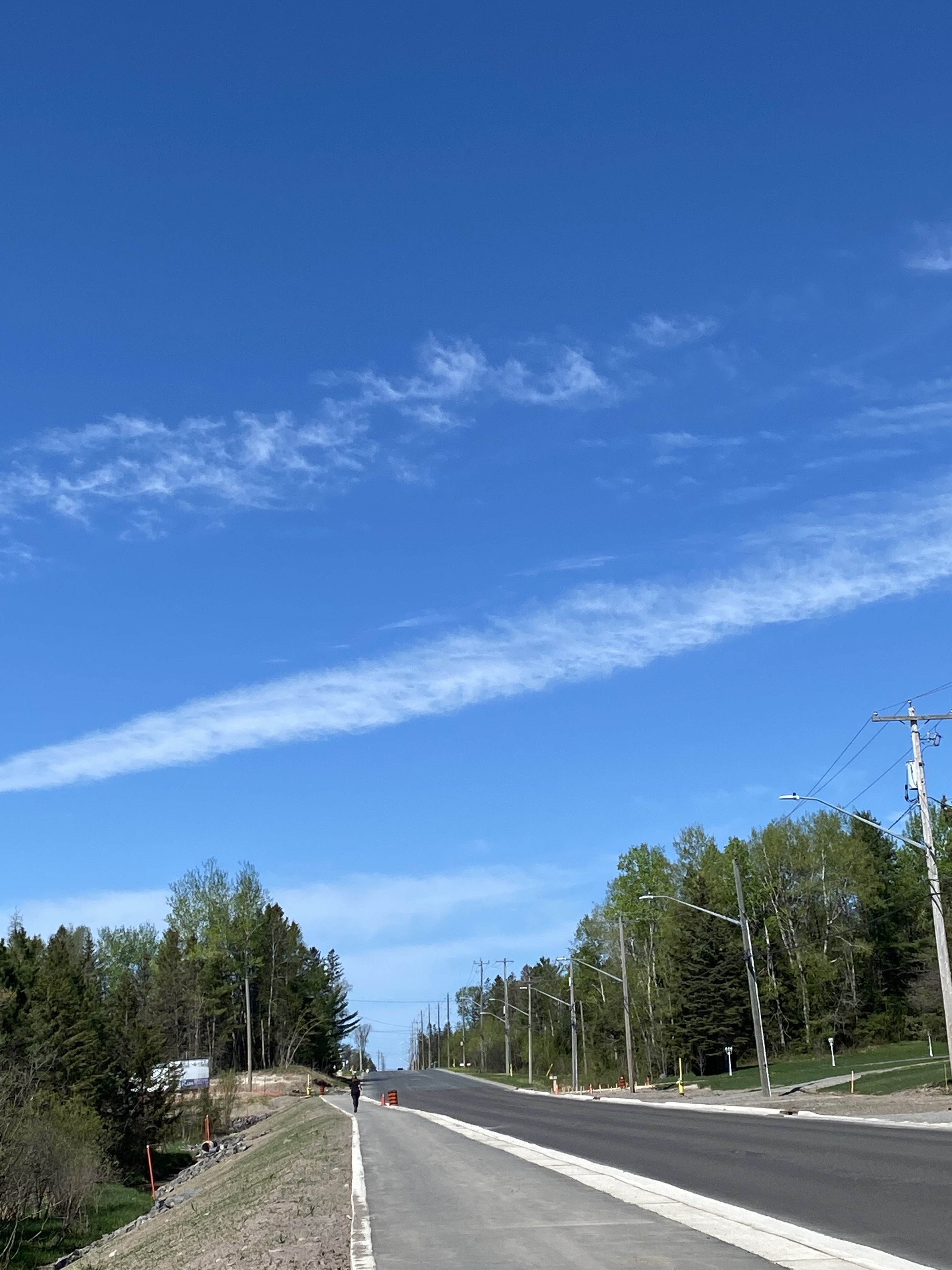 A freshly paved roadway is shown under a bright, blue sky.