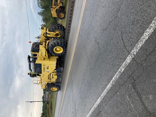 A piece of construction equipment works on a roadway in the County of Lennox and Addington.