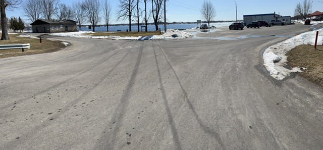The photo shows a parking lot on a sunny winter day next to a lake. 