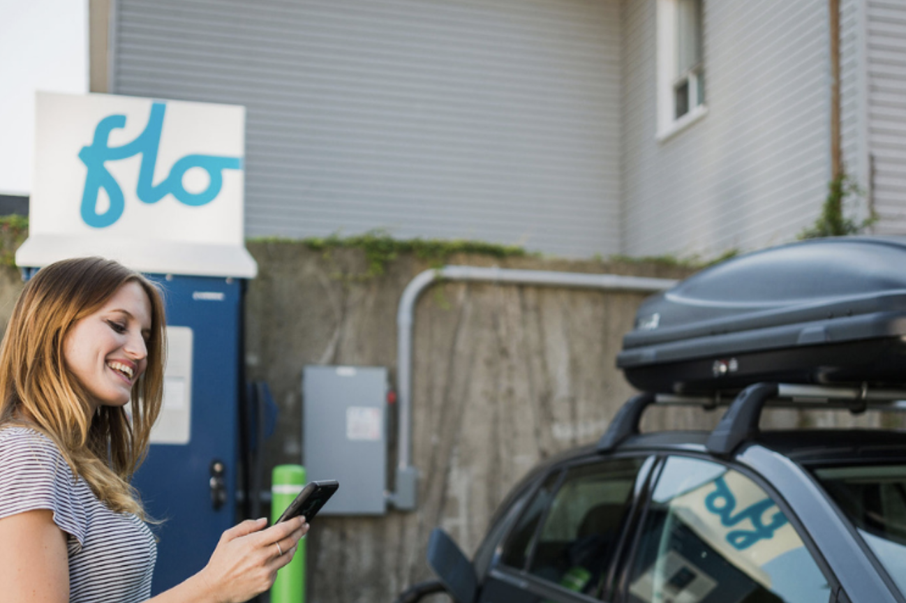 A woman charges her electric vehicle at a charging station. 