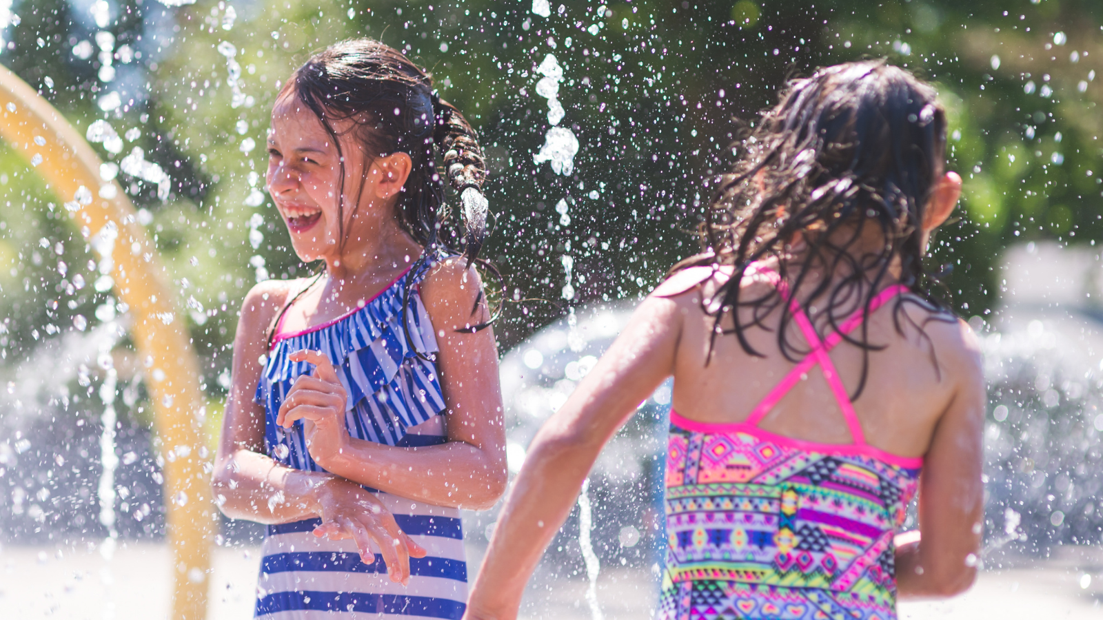 Two small children play at a splash pad. 