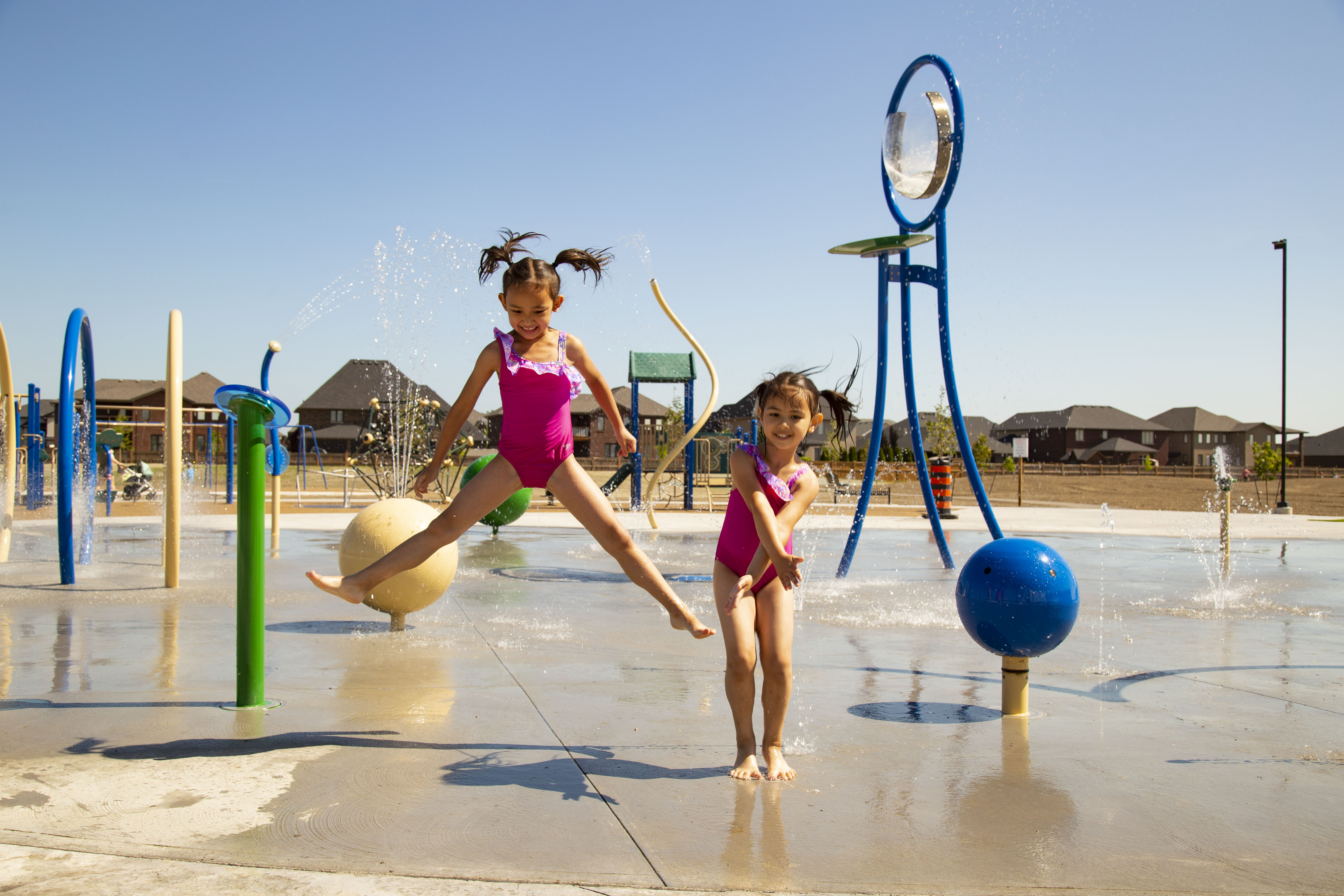 Two kids play at the new splash pad in Lakeshore.