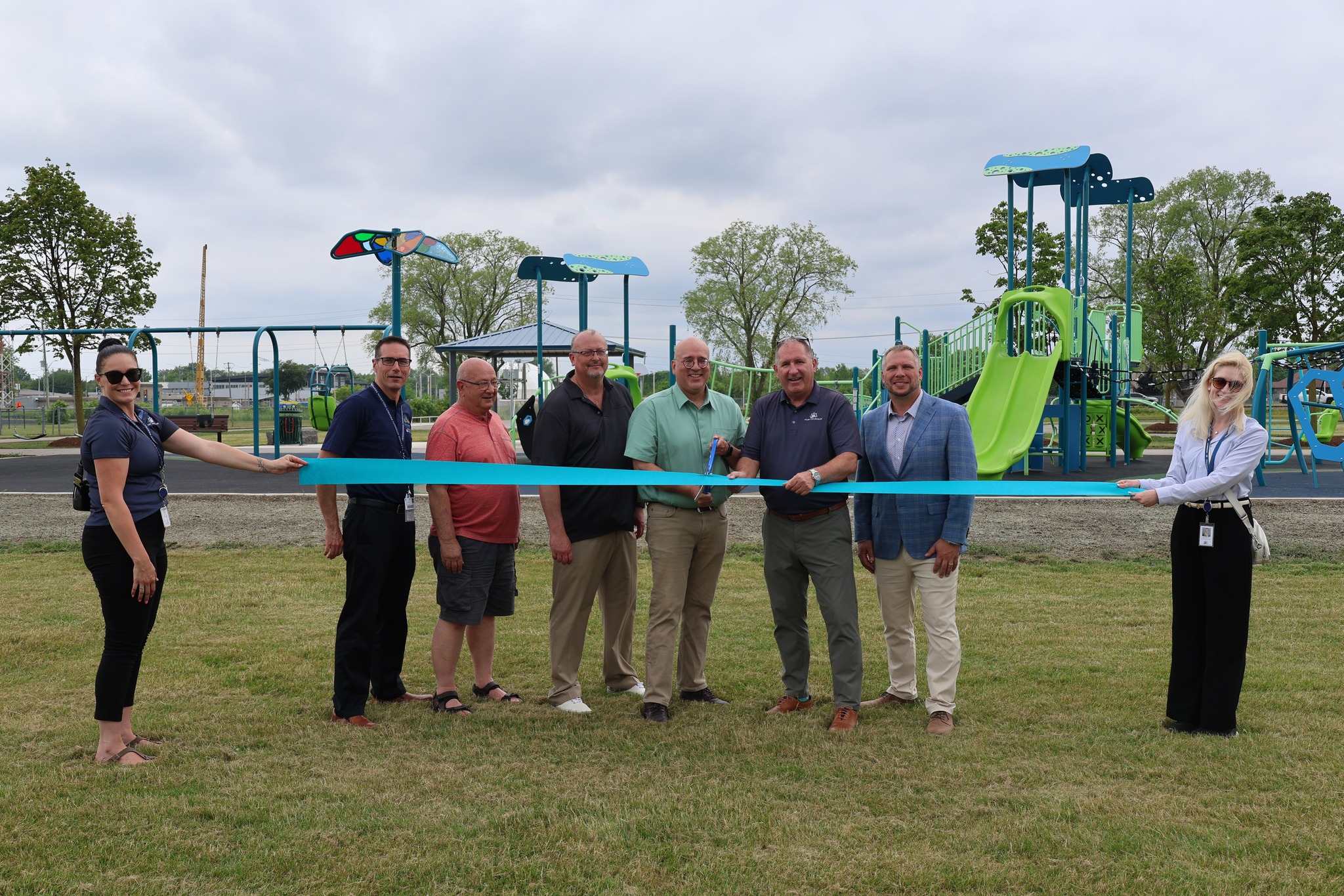 Staff cutting ribbon in front of park