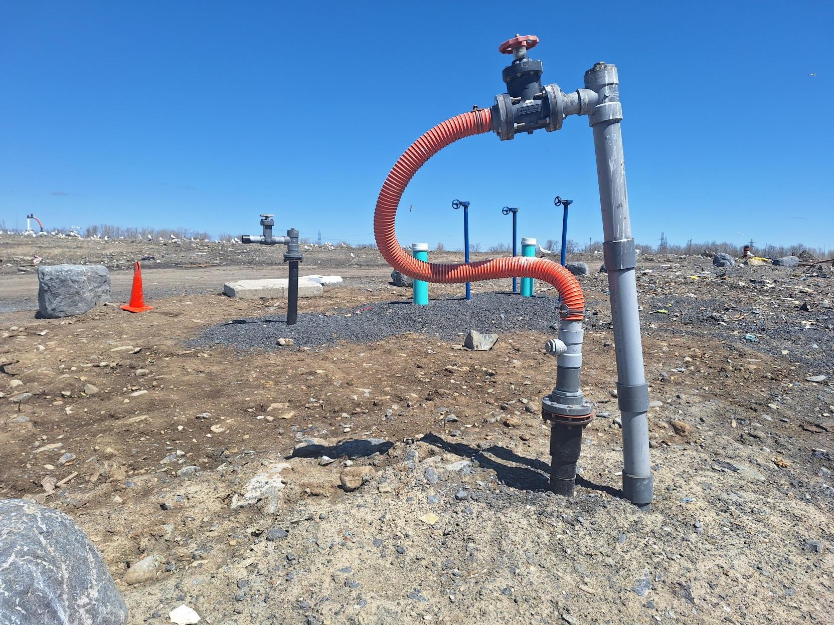 A pipe coming out of rocky ground of a landfill