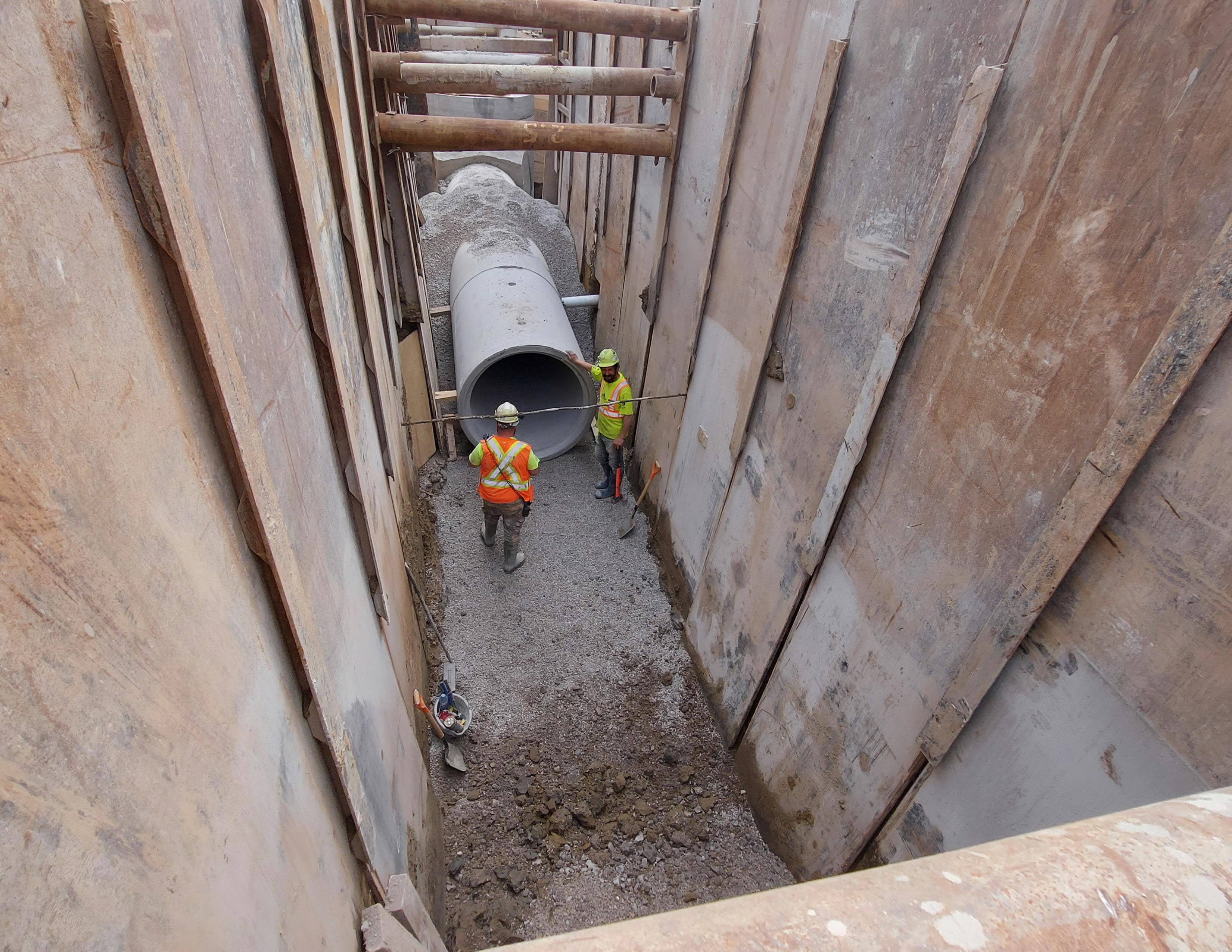 Construction workers install wastewater infrastructure underground on a street in Markham.