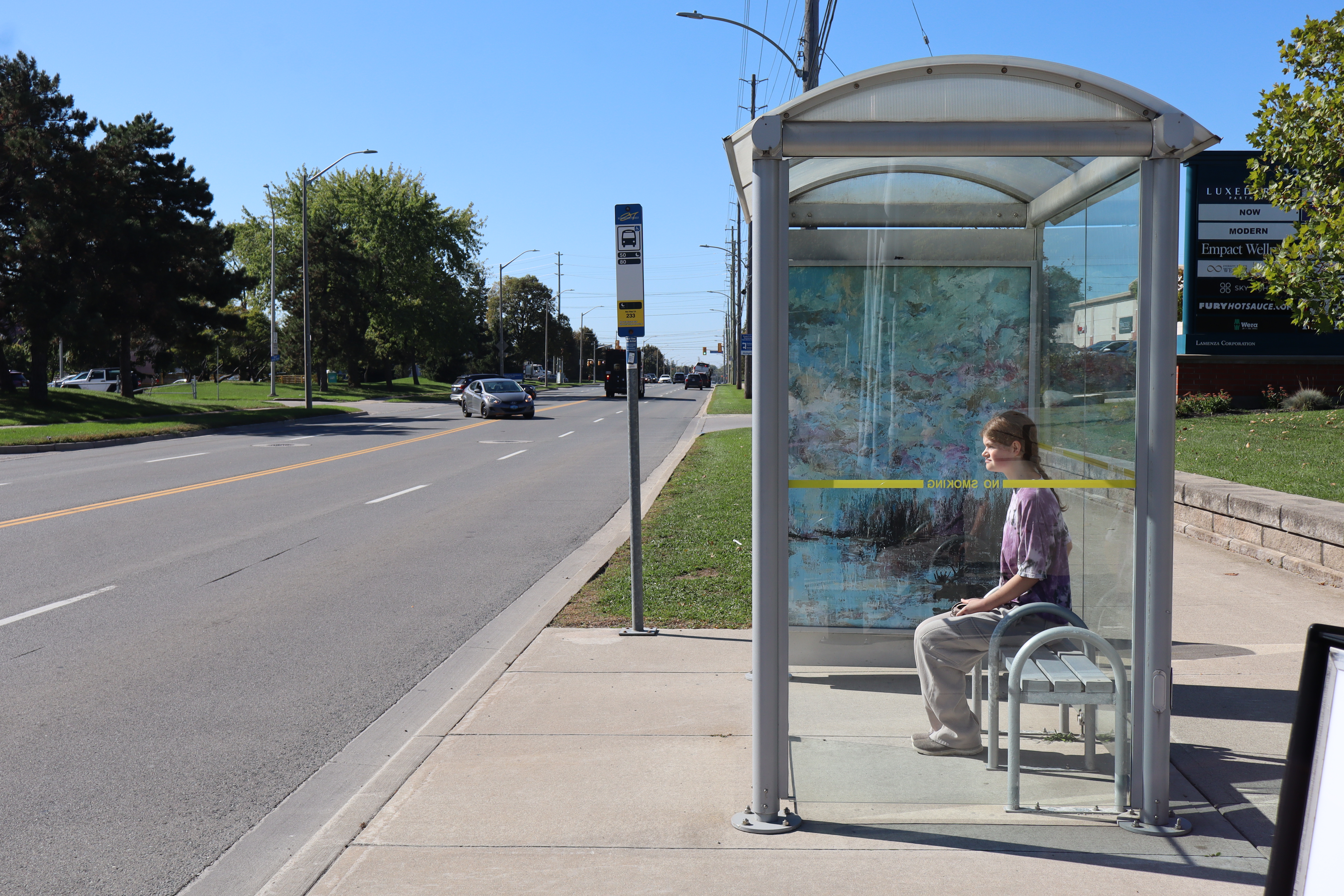 A person sitting at a bus stop shelter