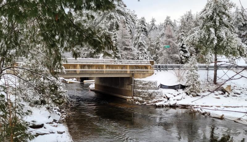 A snow covered bridge running over a river.