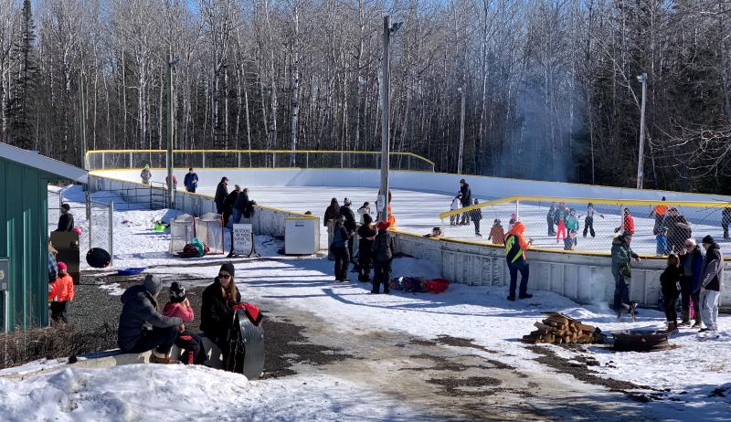 Residents gathered around a skating rink, enjoying an event.