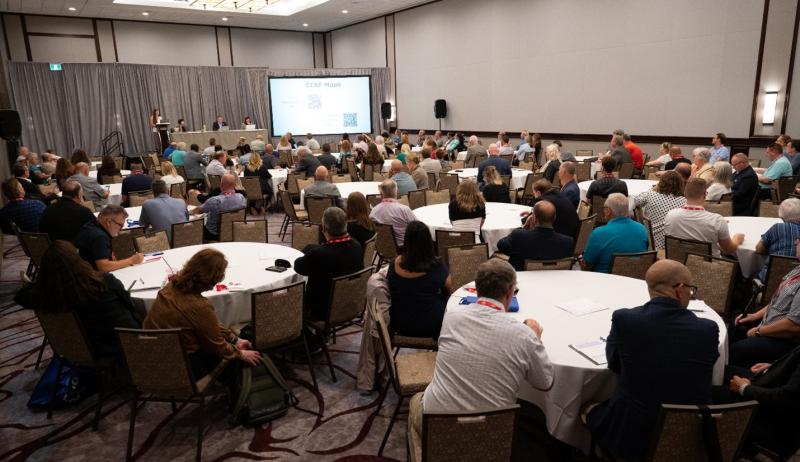 A crowd watching a presentation at the AMO 2025 conference