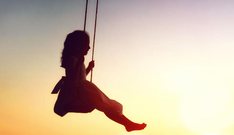 A little girl swings on a swing during sunset hour. 