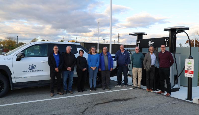 A group of municipal staff standing in front of an electric vehicle charging station