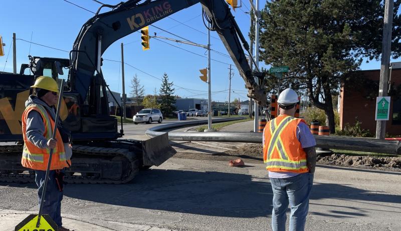 Construction workers guiding a crane to dig a hole in the ground