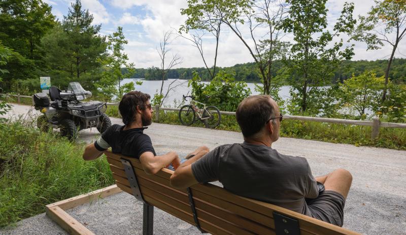 people sitting on a bench by a trail