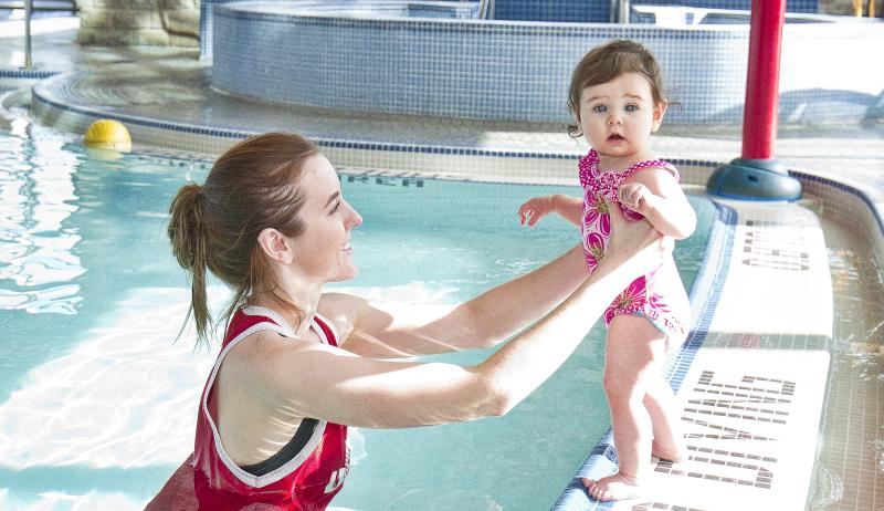 A swim instructor helping a small child swim