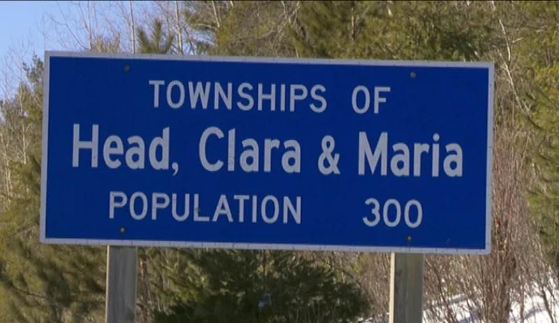 A blue sign that reads "Townships of Head, Clara and Maria, population 300"