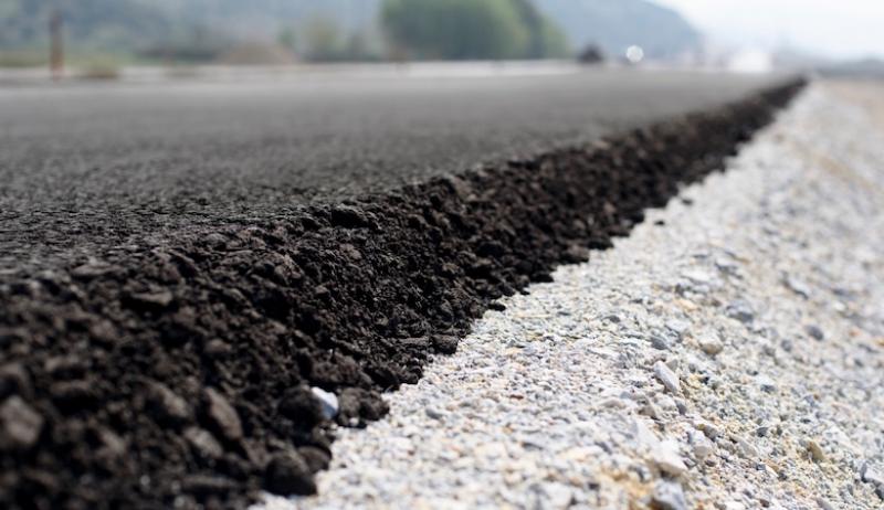 The edge of a road is shown with fresh asphalt. 