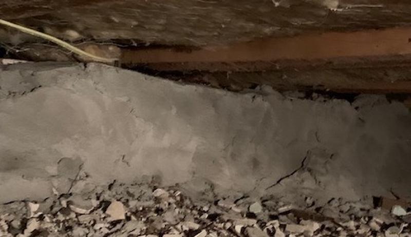 The photo shows the interior foundation of a basement that has been rehabilitated by using new cement. 