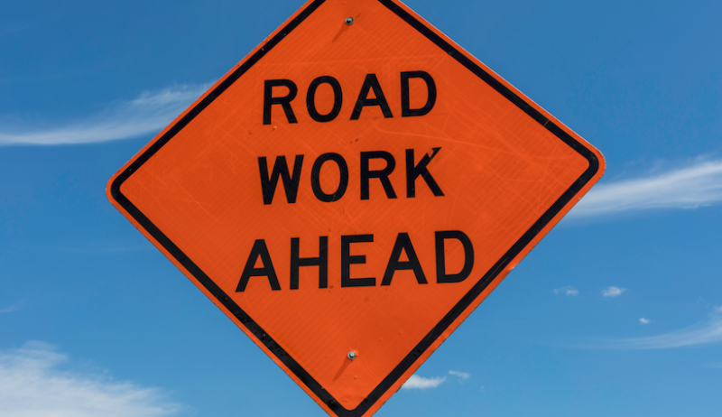 An orange sign that reads "road work ahead".