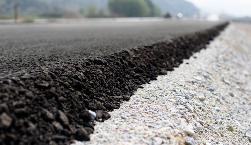 A close-up of asphalt meeting the shoulder of a road. 