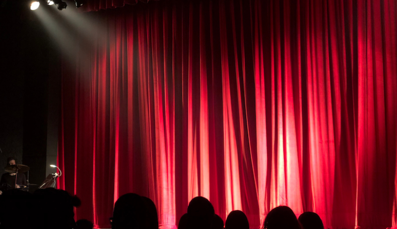 A photo of a light shining on a red curtain at an arts theatre.