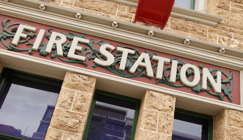 A stock image of a sign on a building that reads "fire station". 