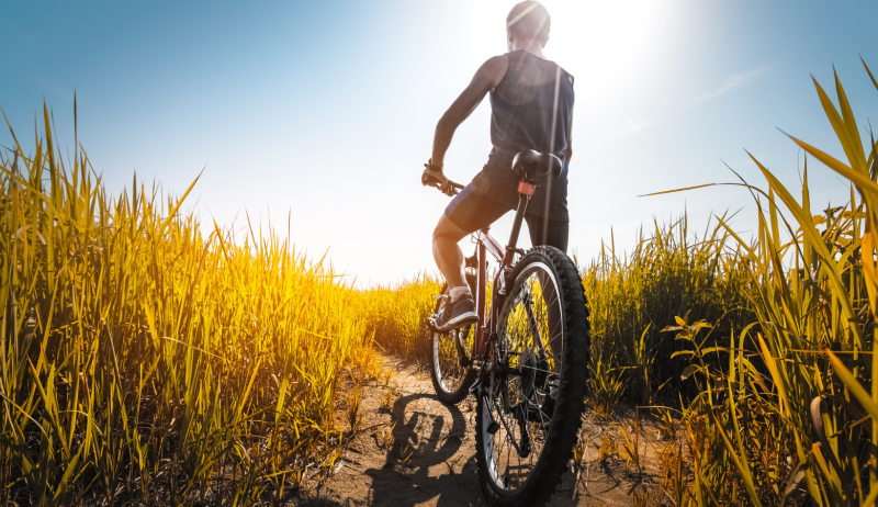 A cyclist bikes on a multi-use trail in the middle of the day. 