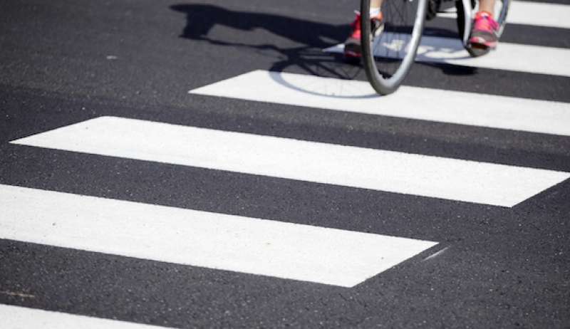 A stock image of a crosswalk with a cyclist. 