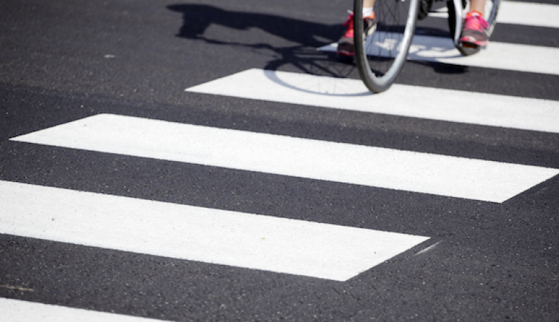 A stock image of a crosswalk with a cyclist. 