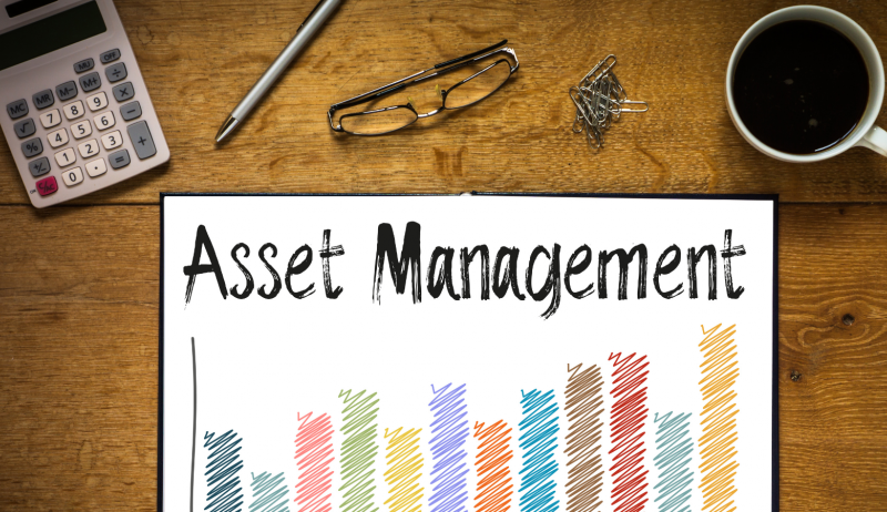 Stock image of a desk with a paper that says "asset management".