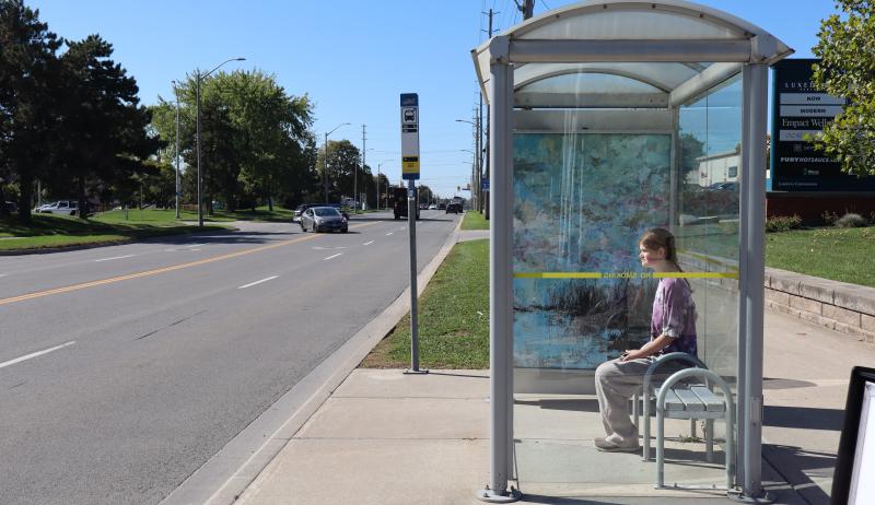 A person sitting at a bus stop shelter