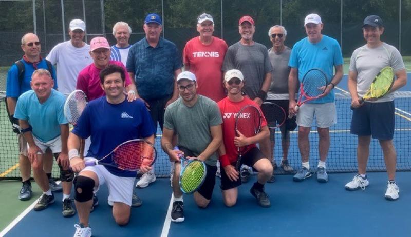 A group posing for a photo on a tennis court